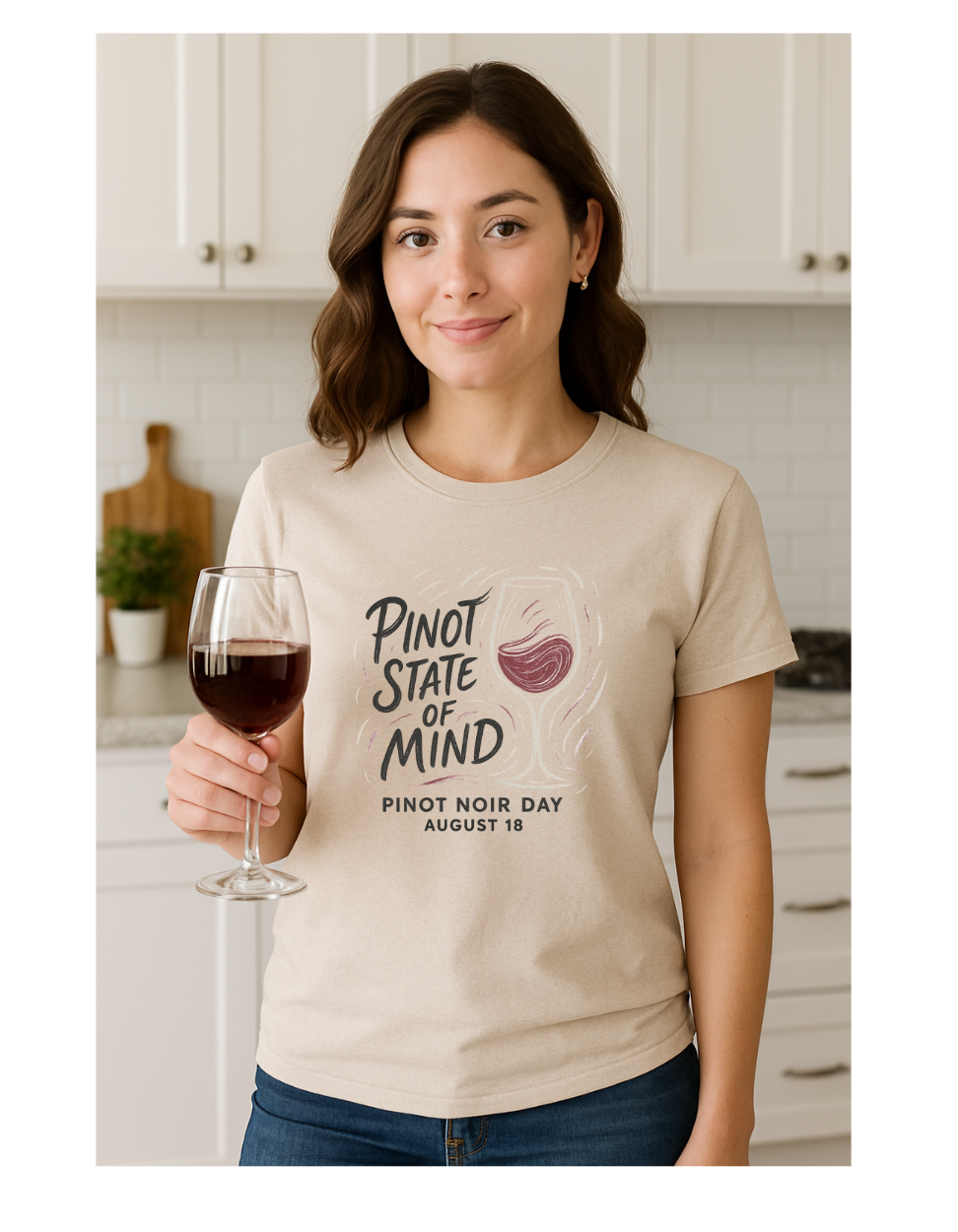 Woman holding a glass of wine wearing a 'Pinot State of Mind' t-shirt in a kitchen.