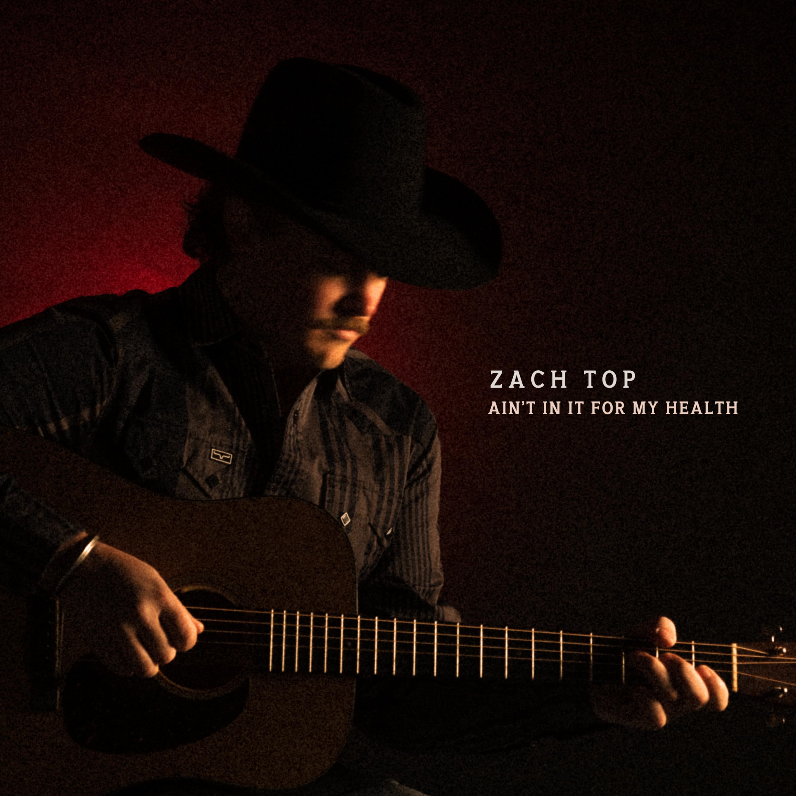 Person playing guitar with 'Zach Top' album title on a dark background